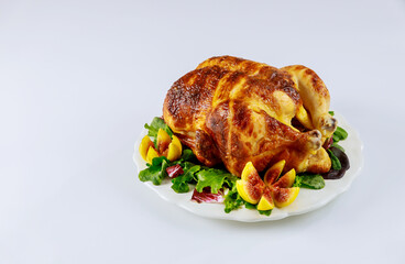 Baked chicken on plate with salad and figs on white isolated background.