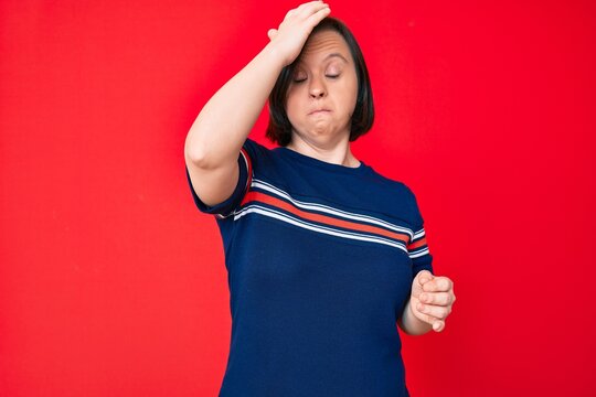 Brunette woman with down syndrome wearing casual clothes surprised with hand on head for mistake, remember error. forgot, bad memory concept.