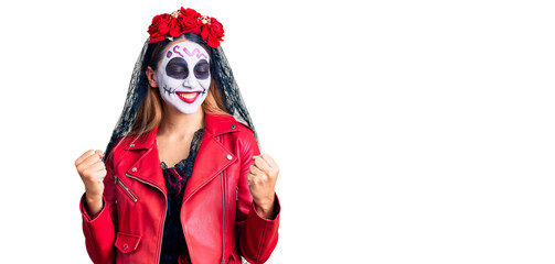 Woman wearing day of the dead costume over background very happy and excited doing winner gesture with arms raised, smiling and screaming for success. celebration concept.