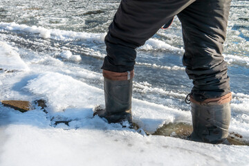 a man walks on thin ice, his feet fall through and break the edge of the ice. Danger of walking on ice in winter