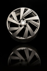 Alloy wheel close-up on a black background. Beautiful grey wheel color and reflection, vertical photo.
