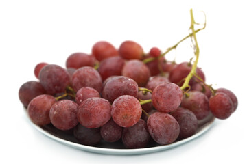 A plate of large red grapes close-up on a white background.