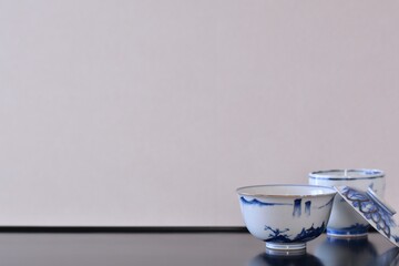picture rice bowl. with picture cup. put on a Japanese lacquer shelf. This is a very fine example of Japanese traditional antique “ imari ware ”. blurred background soft focus image.