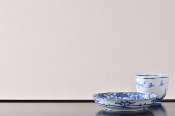 picture plate.  with picture cup. put on a Japanese lacquer shelf. This is a very fine example of Japanese traditional antique “ imari ware ”. blurred background soft focus image.