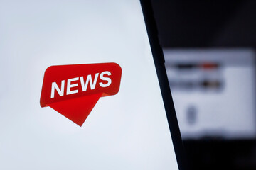 News on the smartphone screen on the background of the monitor.
