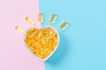 Fish oil capsules in white cup on blue background.