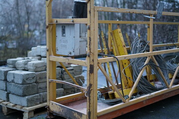 Construction crane for lifting workers to the building. Building blocks are being cut nearby.