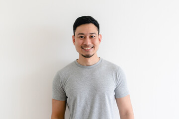 Happy and confident Asian man in grey t-shirt on isolated white background.