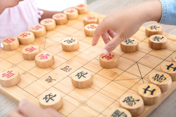 Little girl playing Chinese chess with mother