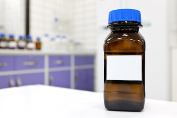 Selective focus of dark glass reagent bottle with unknown clear liquid chemical inside and blank...