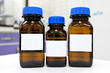 Selective focus of three dark glass reagent bottle with unknown clear liquid chemical inside and...