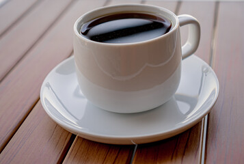 White cup of black coffee on a wooden table.