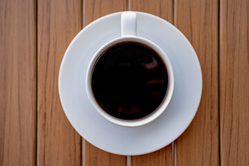 White cup of black coffee on a wooden table.