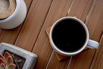 Black coffee cup on a wooden base.