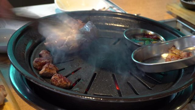 Pork Belly Being Grilled On Charcoal Griller In Korean Restaurant. - close up