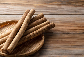 Burdock in a bamboo colander placed in the background of a wooden board