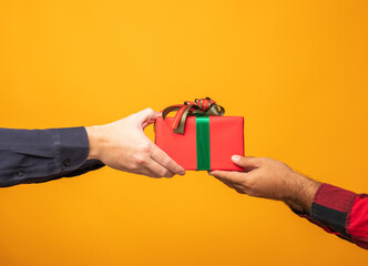 Close up hands giving the present gift box in christmas day on yellow background. Merry christmas and happy new years and sending the gift.