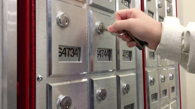 Woman finding the key to open pobox inside post office with 4k resolution