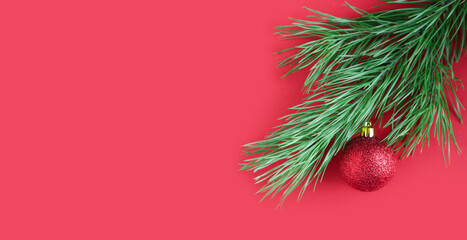 Banner pine branch decorated with a shiny red ball on a red background. Christmas or New Year concept. Minimalism