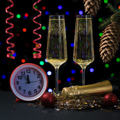 Sparkling wine glasses, red streamers and red clock on a bokeh background.