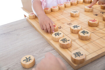 The child is playing Chinese chess seriously