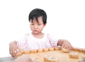A three-year-old Chinese girl in front of a white background is playing Chinese chess