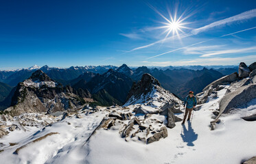 Winter sport activity. Adventurous male hiker climbing up a snow covered mountain with the sun shinning.
