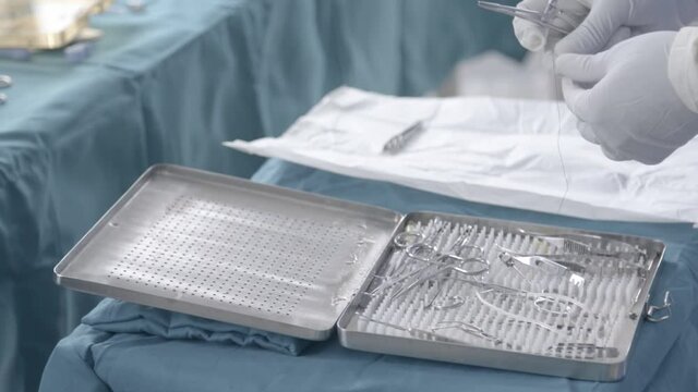 Nurse preparing stainless steel wire on tweezers on little table