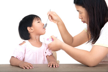 Young mother feeding her daughter in front of white background