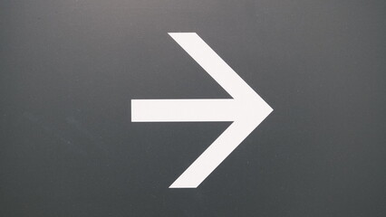 white arrow pointing right on a gray background in the train station