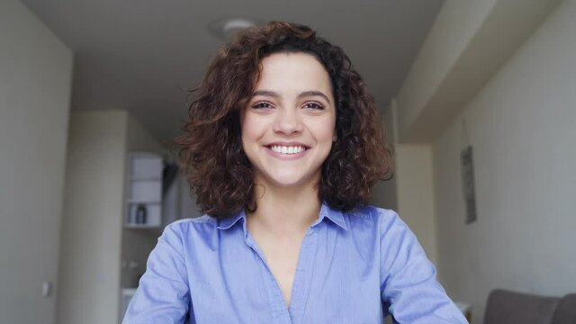 Close-up portrait of beautiful smiling young woman looking at camera at home.