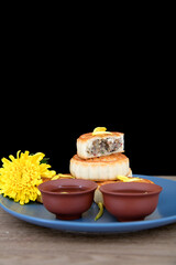Mooncakes, tea and a chrysanthemum are placed on the plate in front of the black background