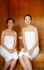 サウナで座るタオルを巻いた母娘