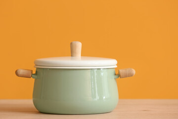 Cooking pot on table against color background