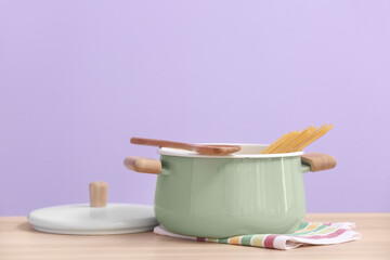 Cooking pot on table against color background