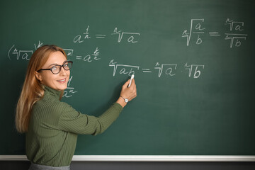 Mature maths teacher near blackboard in classroom