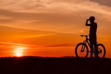Naklejka na ściany i meble silhouette of a mountain biker at sunset