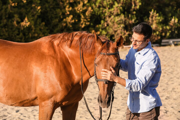 Young man with cute horse outdoors