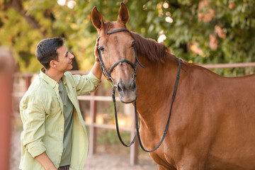 Young man with cute horse outdoors