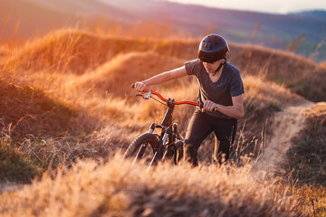 Fototapeta na wymiar A young cyclist pushing a mountain bike through the hills