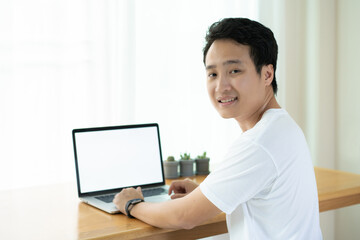 Happy Asian young businessman working at home and looking at the camera