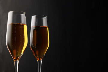 Two glasses of champagne, wine on a black background, a place for text on the right, copypace. New year and Christmas background