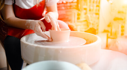 Female hands crafting a pottery cup on a potter's wheel. Handmade and crafting concept. Top horizontal view copyspace.