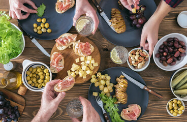 Top view of three people having dinner together on rustic wooden table. Friends having dinner concept