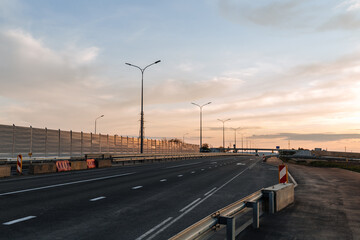 Newly built road with soundproof panels against the background of sunset