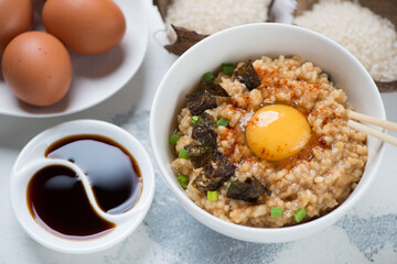 Bowl of tamago kake gohan or japanese rice mixed with a raw egg and topped with an egg yolk, studio shot on a white concrete surface