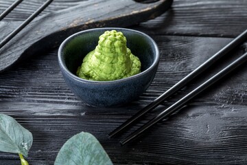 wasabi in a ceramic saucepan. Black wooden background and decor.