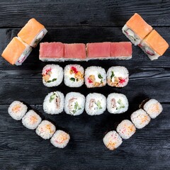 A set of eight types of Japanese sushi rolls on a black wooden background. Top view.