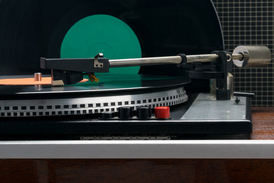 against the background of a column and a vinyl record, retro turntable with a red button