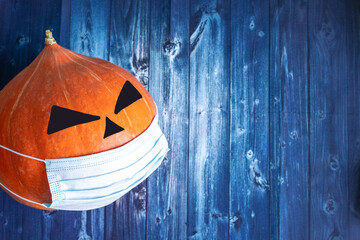 halloween pumpkin in medical mask from COVID-19 on a wooden background